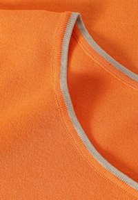 Oranžová textilie se zaobleným výstřihem s kontrastním šedým žebrovaným lemem. Textura je pletená s hladkým povrchem.