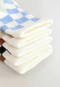 Färggranna rutiga strumpor staplade prydligt, med blå och vita rutor, mjuk textur, på en krämfärgad bas och varierande färger på toppstripen.