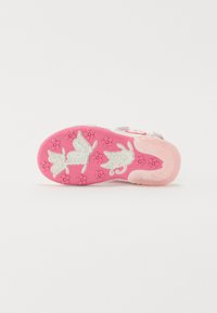 Barnes sålesole med en livlig rosa farge med blomster- og sommerfugl mønstre; laget av fleksibel gummi med en strukturert overflate.