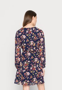 Vestido floral com manga longa, base azul-marinho, padrão de flores multicoloridas, cintura ajustada e saia volumosa. Tecido leve.