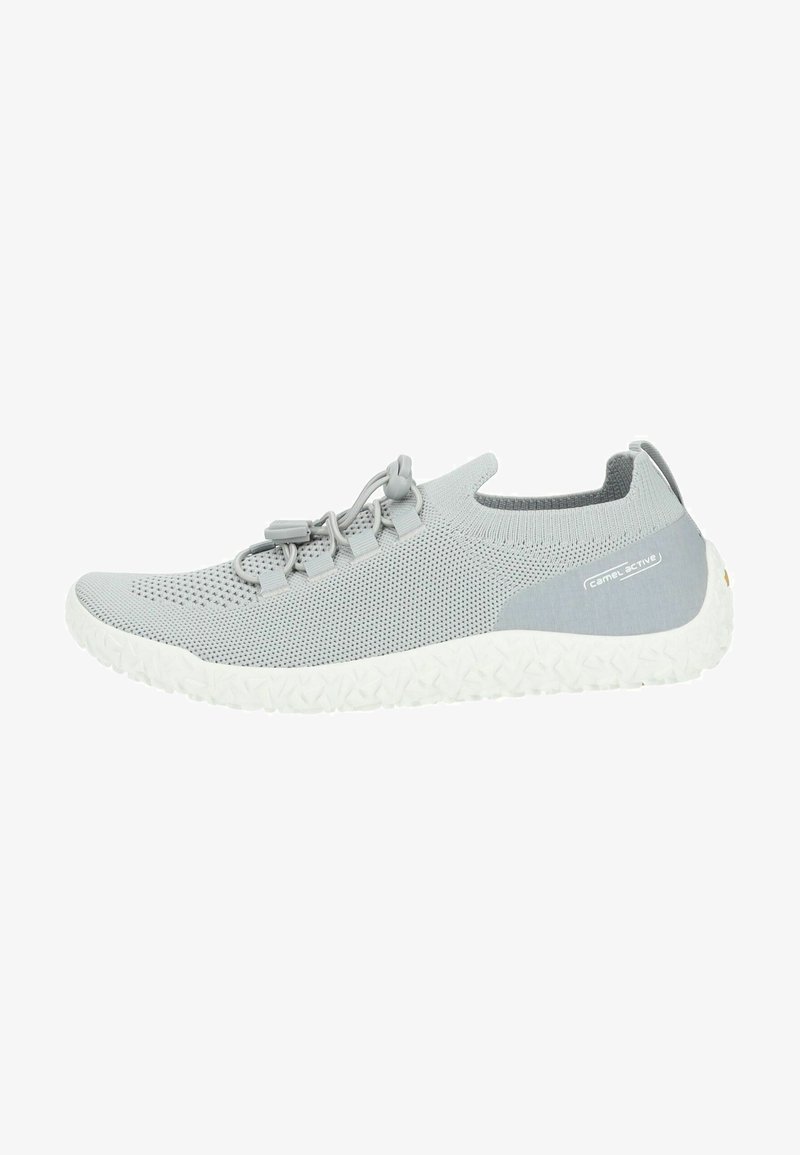 Scarpa sportiva grigia chiara realizzata in materiale a rete traspirante. Presenta lacci elastici e una suola in gomma bianca testurizzata con accenti a motivi.