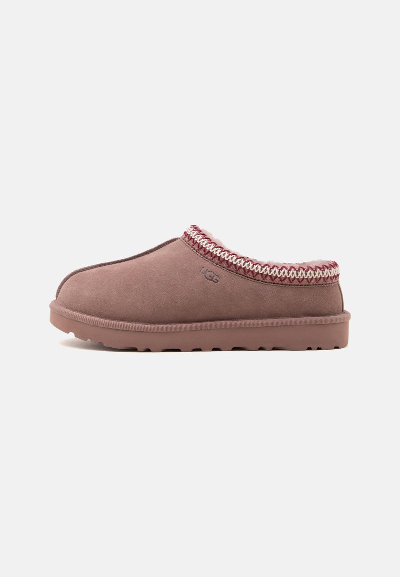 Chaussons UGG marron à enfiler avec bordure tressée et doublure douce, semelle plate et logo UGG sur le côté.