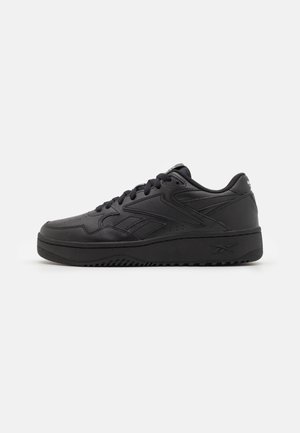 Baskets basses en cuir noir avec fermeture à lacets, logo de marque sur le talon et le côté, et semelle en caoutchouc texturée.