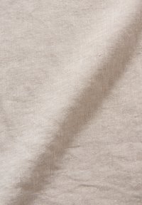 Tessuto in lino color beige chiaro con una superficie testurizzata, che mostra una tessitura morbida e naturale e sottili variazioni di colore.