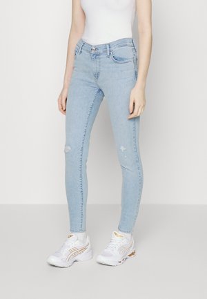 Jeans skinny bleu clair en denim, avec une finition délavée, un léger effet usé au niveau des genoux et un design classique à cinq poches.