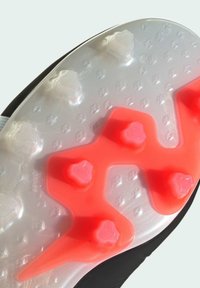 Sole di scarpa da calcio nera con parte superiore traslucida, caratterizzata da quattro tacchetti trasparenti e tre tacchetti esagonali rosa disposti in un motivo distintivo.