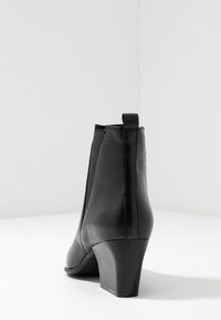 Schwarze Leder-Ankle-Boots mit runder Spitze, elastischen Seitenteilen und mittelhohem Blockabsatz. Verfügt über eine Zuglasche an der Rückseite.