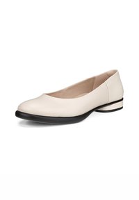 Ljus beige läderballetsko med rund tå, svart gummisula och låg klack som har en subtil svart accent vid basen.