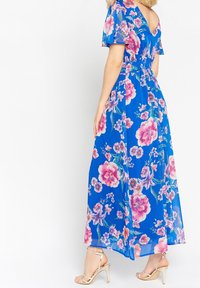 Maxi šaty v jasně modré barvě s květinovým vzorem v růžové a fialové. Mají volánové rukávy a výstřih do V na zádech. Dokončené jemným řasením.