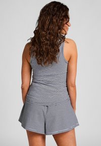 Grijze gestreepte tanktop en bijpassende uitlopende shorts. De stof lijkt zacht en rekbaar, met dunne strepen en een comfortabele pasvorm.