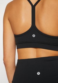 Zwarte sportbeha met een racerbackontwerp, voorzien van een textuurband en een klein logo-accent op de achterkant.