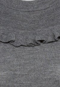 Pull gris en maille avec un col à volants et un col côtelé, montrant la texture et le motif du tissu.