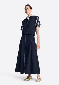 Tumesinine kleit, millel on lühikesed triibulised varrukad, lukuga krae ja volditud seelik. Pehme tekstuur, kuldse aktsendiga keskmise õmbluse ääres.