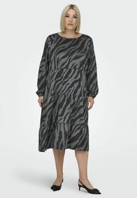 Pitkä, kerroksellinen mekko musta-harmaan seeprakuosisena, jossa on pitkät hihat, pyöreä pääntie ja pehmeä, valuvatekstuuri.