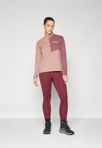 Terrex langermet topp i rosa gradient med kvart glidelås og logo, parret med bordeaux leggings. Strukturelt stoff med tettsittende design.