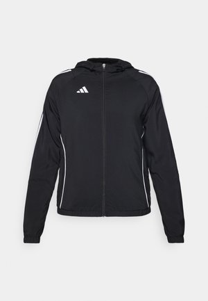 Sort atletisk jakke med lynlås foran, hætte og hvide striber langs ærmerne. Har et Adidas-logo på øverste venstre side.