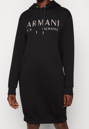Robe à capuche noire à manches longues avec le texte « ARMANI A|X EXCHANGE » sur le devant et capuche à cordon portée par une personne.