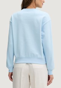 Felpa azzurro chiaro con girocollo e vestibilità comoda, polsini e orlo a coste, realizzata in materiale morbido con una trama liscia.