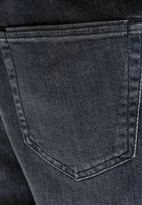 Detailný záber na zadné vrecko čiernych riflí zobrazujúci textúru látky a dvojité prešitie švov.