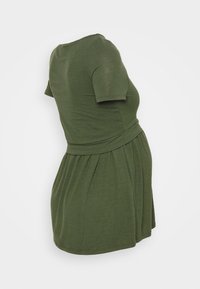 Maternity dress in olive green with short sleeves, fitted waist, and gathered skirt, displayed on a headless mannequin against a white background.