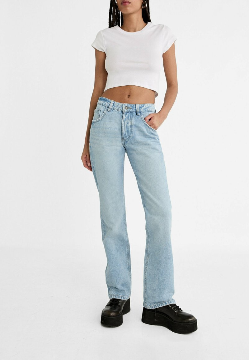 Jeans dritti azzurro chiaro con vita alta, lavaggio sbiadito e design a cinque tasche. Abbinate a una t-shirt bianca cropped e scarpe platform nere.