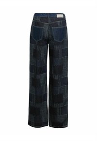 Pantalons en denim à jambes larges avec un design en patchwork dans un bleu foncé, présentant diverses textures et motifs, y compris des rayures et des pois.