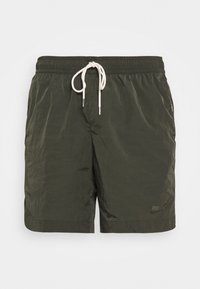 Plavecké šortky Nike v tmavě zelené barvě, vyrobené z lehké texturované tkaniny. Mají stahovací pás s krémovými tkaničkami a jemným logem.