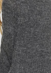 Šedý svetr s texturou z měkkého, chlupatého materiálu. Má žebrovaný pletený vzor a volnější střih. Vhodný pro běžné nošení.