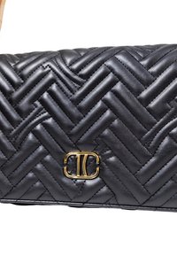Clutch in pelle nera trapuntata con motivo a zigzag diagonale e piccolo emblema metallico dorato centrato sul flap anteriore.