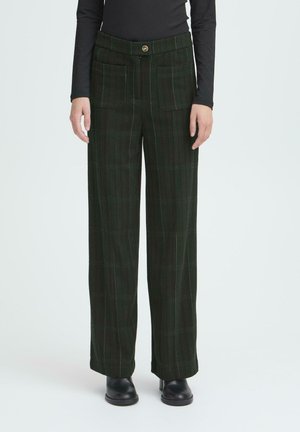 Green plaid trousers with a high waist, wide legs, two front pockets, and contrasting stitching detail. Worn with black ankle boots.