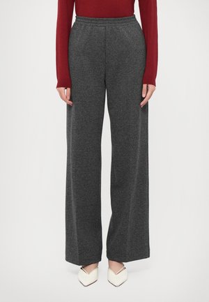Pantalons large en chevron gris avec une ceinture élastique, associés à un haut rouge ajusté et des ballerines blanches à bout pointu.