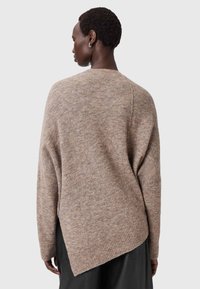 Maglione beige a maglia con vestibilità rilassata, orlo a coste e design high-low. Texture morbida e delicato motivo marmorizzato sono visibili.