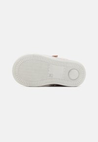 Gummisneaker-Sohle mit strukturiertem Muster, hellgrauer Farbe und kreisförmigem Akzent. Verfügt über ein Zickzack-Griffdesign für bessere Traktion.