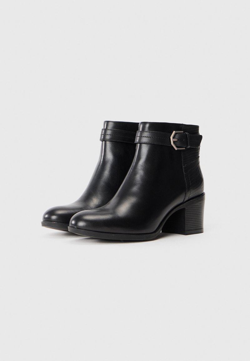 Bottines en cuir noir avec un bout rond, un talon épais et une sangle décorative avec une boucle en argent sur le côté.