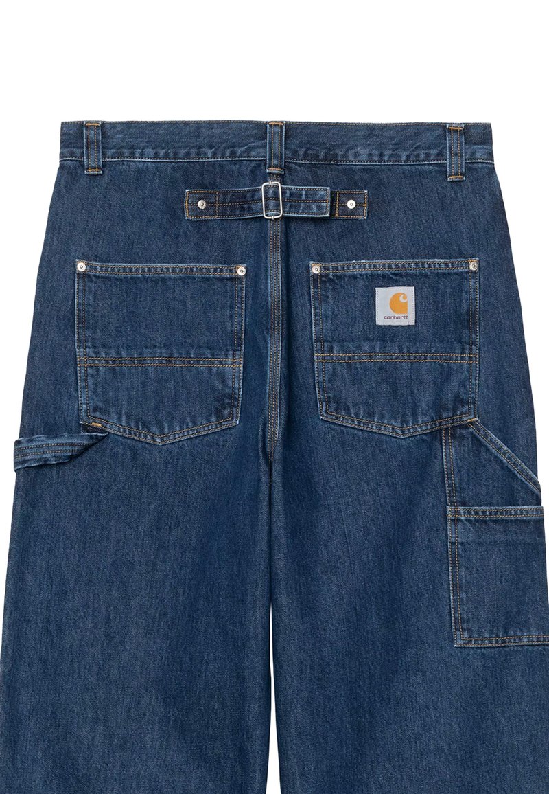 Pantalon de travail en denim avec boucle réglable à l'arrière, deux poches arrière et une poche latérale supplémentaire avec le logo Carhartt sur la poche arrière droite.