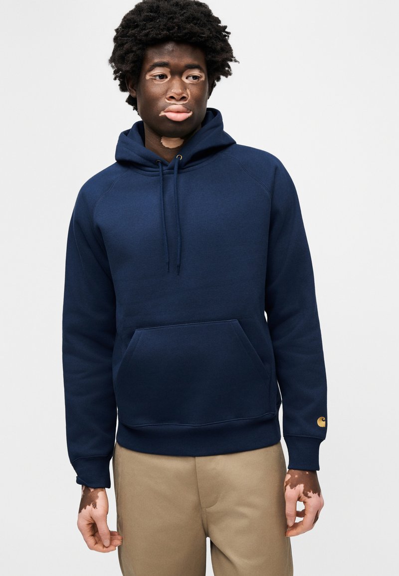 Sweat à capuche bleu marine en mélange de coton ; il présente une poche kangourou à l'avant, des poignets côtelés et un petit logo sur la manche.