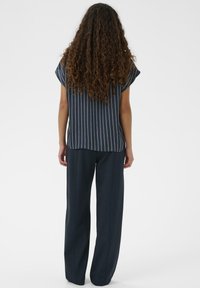 Tengerészcsíkos felső rövid ujjakkal, magas derekú, bő szárú tengerészkék nadrággal párosítva. Simított szövettextúra kontrasztos fehér csíkokkal.