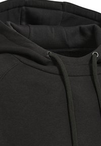 Zbliżenie na czarną bluzę z kapturem z wyściełaną podszewką, z troczkami przewleczonymi przez metalowe oczka przy dekolcie.