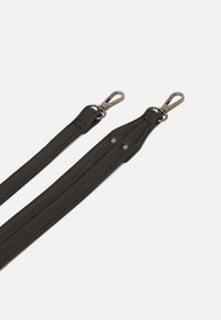 La correa de la bolsa de cuero negro presenta una superficie texturizada, dos clips metálicos en cada extremo y remaches para mayor durabilidad.