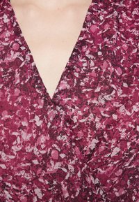 Tmavě fialové zavinovací šaty s výstřihem do V, texturovaná látka s květinovým vzorem v odstínech růžové a černé. Měkký, splývavý materiál.