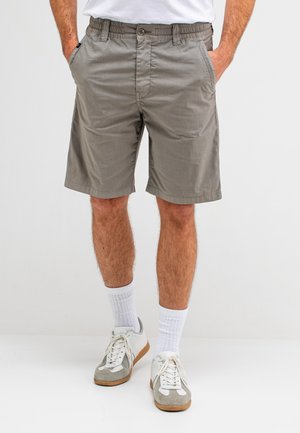 Grijze katoenen shorts met een elastische tailleband, twee zijzakken en een knoopsluiting. Geloofd met witte sokken en grijze schoenen.