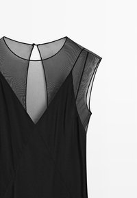 Zwarte jurk met doorschijnende kapmouwtjes, V-hals en een sleutelgatopening aan de achterkant; heeft een gladde stof met een gestructureerde pasvorm.