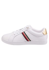 Białe sneakersy z gładkiej skóry, z cienką czerwoną, granatową i kremową wstążką oraz złotym akcentem na pięcie. Okrągły kształt noska.