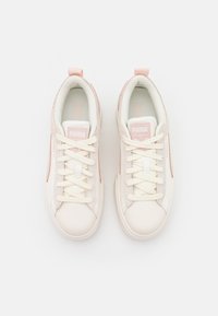 Baskets blanches et rose clair avec une tige synthétique lisse, des accents texturés, des lacets plats et un col rembourré. Logo sur la languette.