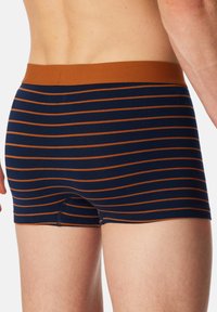 Donkerblauwe boxershorts met horizontale oranje strepen en een effen bruine tailleband. Zachte stof met een aansluitend ontwerp en geen zichtbare sluitingen.