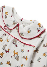 Robe en coton avec une base blanche, présentant un imprimé animalier ludique. Elle a un col bordé de rouge et des plis pincés sous l'encolure.