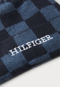 Sininen ja laivansinisekirjava neulottu pipo, jossa on pehmeä rakenne. Edessä valkoista "HILFIGER" -kirjontaa.