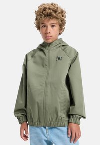 Olivinvihreä huppari, jossa on joustavat hihansuut ja helma, edessä vetoketju ja logo ylhäällä rinnassa. Silkkinen kangas, rento malli.