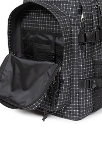 Czarna plecak z wzorem w kratkę. Posiada otwartą komorę, siatkową kieszeń i różne paski. Wykonany z trwałego materiału o gładkiej strukturze.