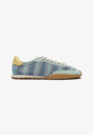 Sneaker tissé bleu clair et violet avec embout en daim, lacets beiges, patch jaune au talon et semelle en caoutchouc marron texturée, présenté de profil.